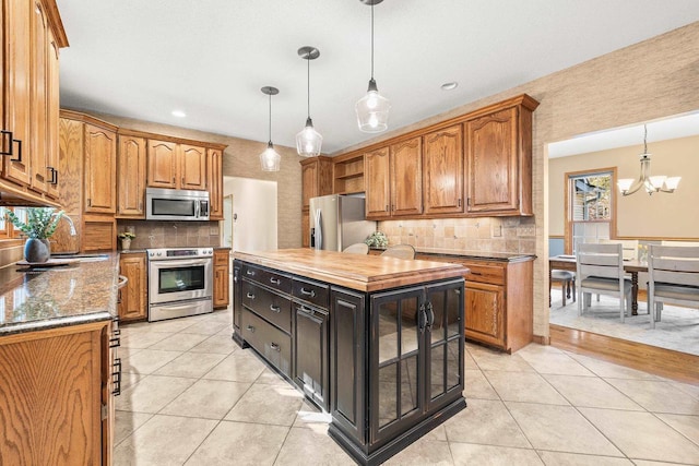 kitchen with stainless steel appliances, brown cabinets, light tile patterned flooring, and a center island