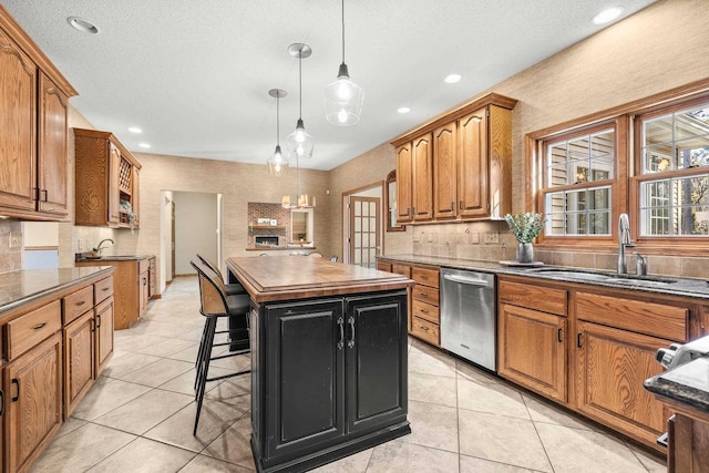 kitchen with dishwasher, a sink, brown cabinets, and a kitchen island