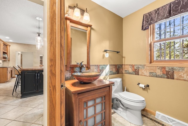 bathroom featuring visible vents, tile walls, toilet, tile patterned floors, and vanity