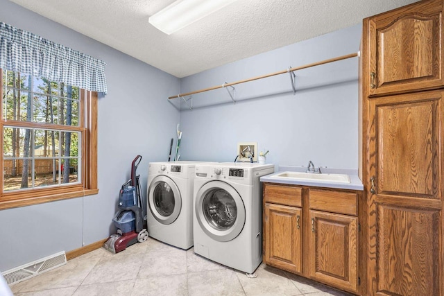 laundry room featuring visible vents, cabinet space, a sink, a textured ceiling, and washing machine and dryer