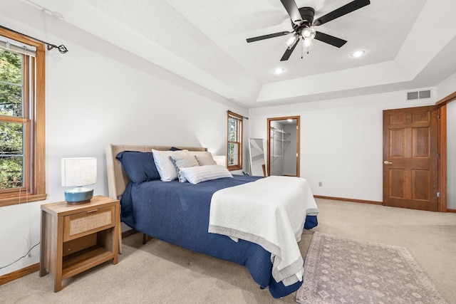 bedroom featuring light carpet, visible vents, baseboards, and a tray ceiling