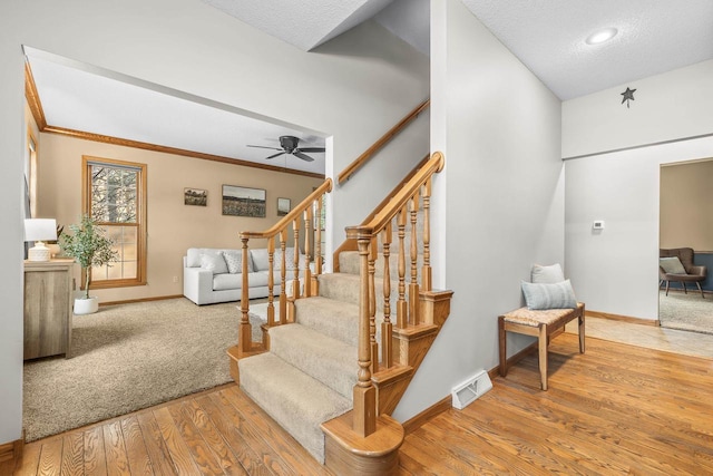 staircase featuring hardwood / wood-style flooring, baseboards, visible vents, and a textured ceiling