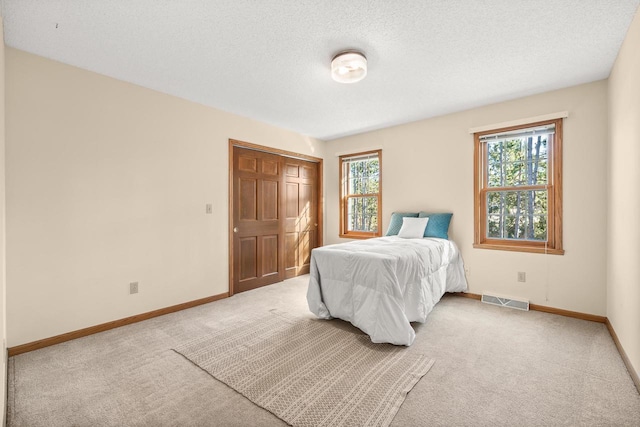 bedroom with visible vents, multiple windows, light colored carpet, and baseboards