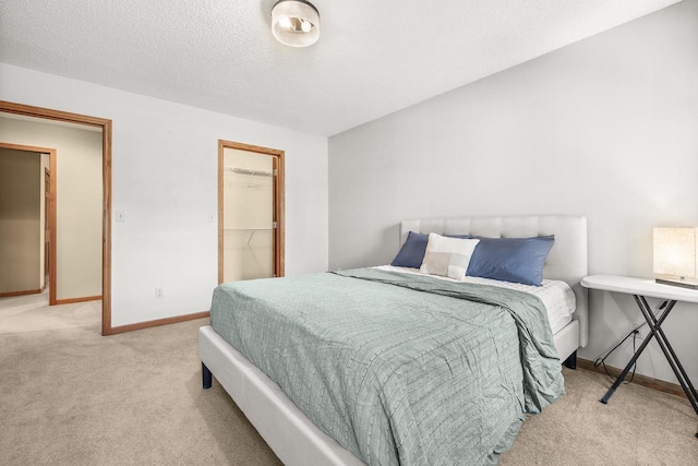 bedroom with baseboards, carpet floors, a textured ceiling, and a spacious closet