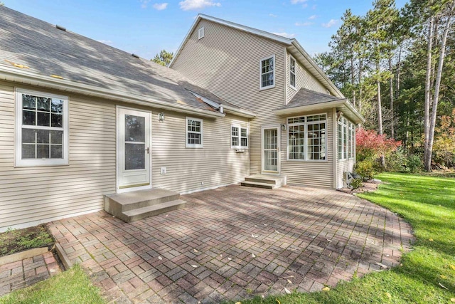 rear view of property with a patio area, a yard, a shingled roof, and entry steps