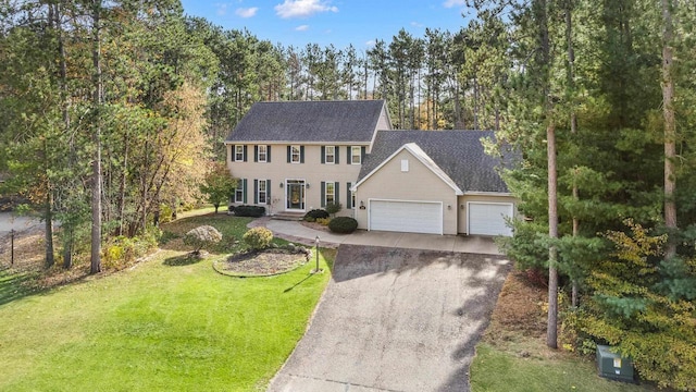 colonial home with an attached garage, gravel driveway, and a front yard