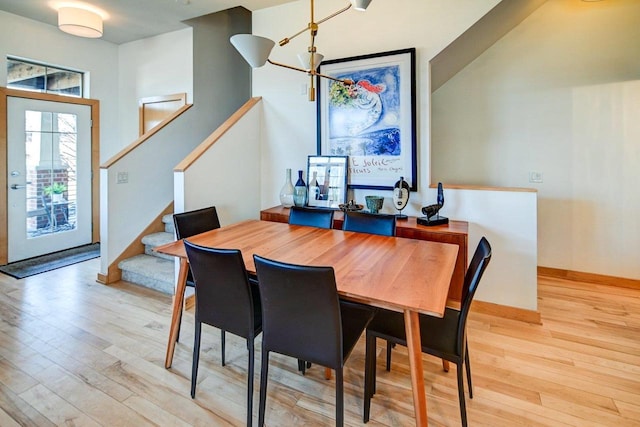 dining space featuring baseboards, light wood-style floors, and stairs