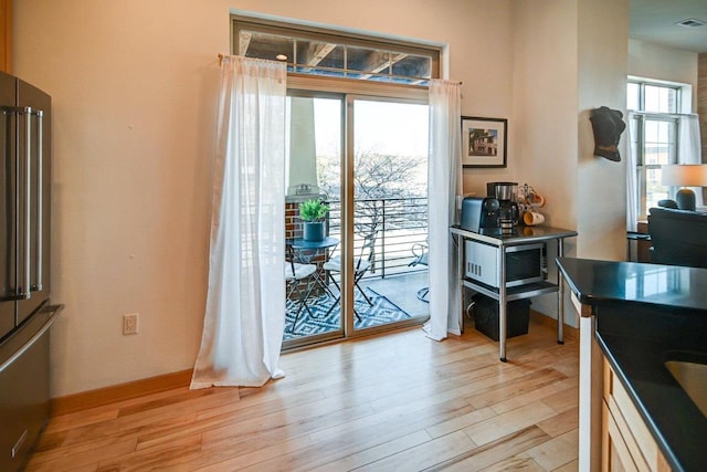 doorway to outside with light wood finished floors and baseboards