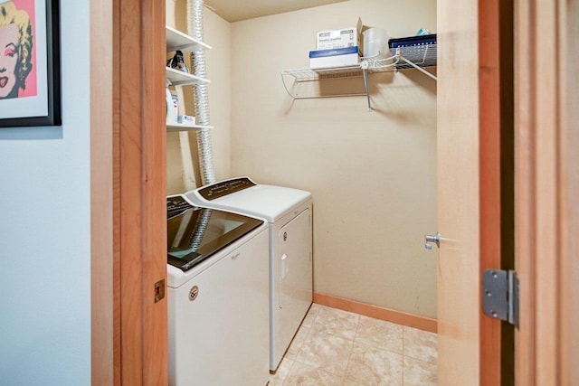 washroom featuring washer and dryer, baseboards, laundry area, and light tile patterned floors