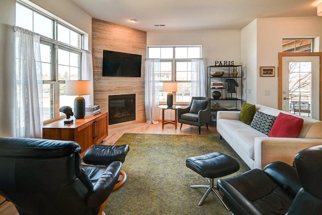 living room with visible vents, a large fireplace, and light wood finished floors