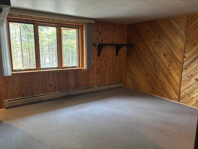 unfurnished room with a baseboard heating unit, carpet, and wood walls