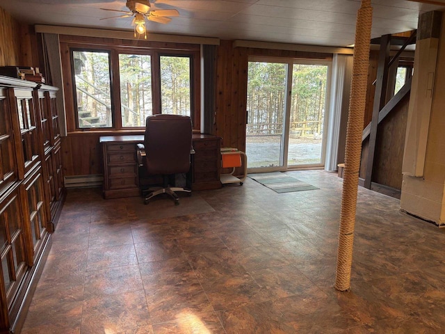 home office featuring wooden walls, baseboard heating, and ceiling fan