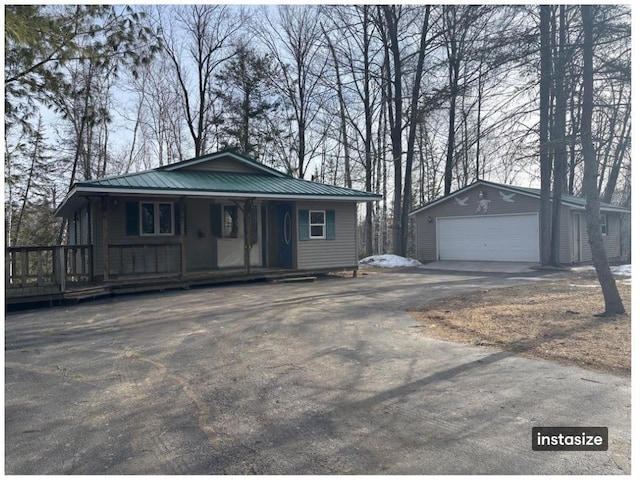 view of front facade with metal roof, a detached garage, an outbuilding, and covered porch