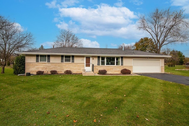 ranch-style home featuring aphalt driveway, an attached garage, and a front yard