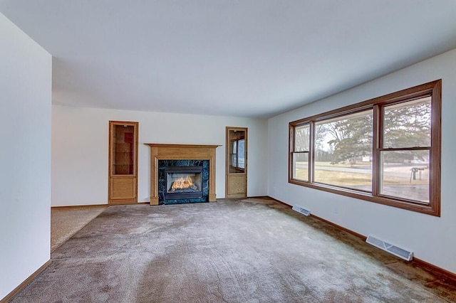 unfurnished living room with carpet, visible vents, and baseboards