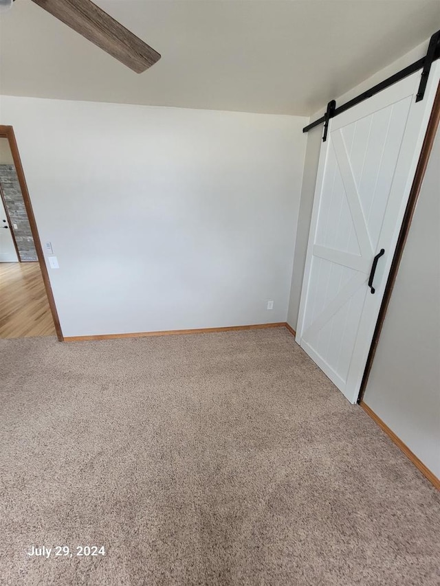 interior space featuring a barn door, baseboards, and light carpet