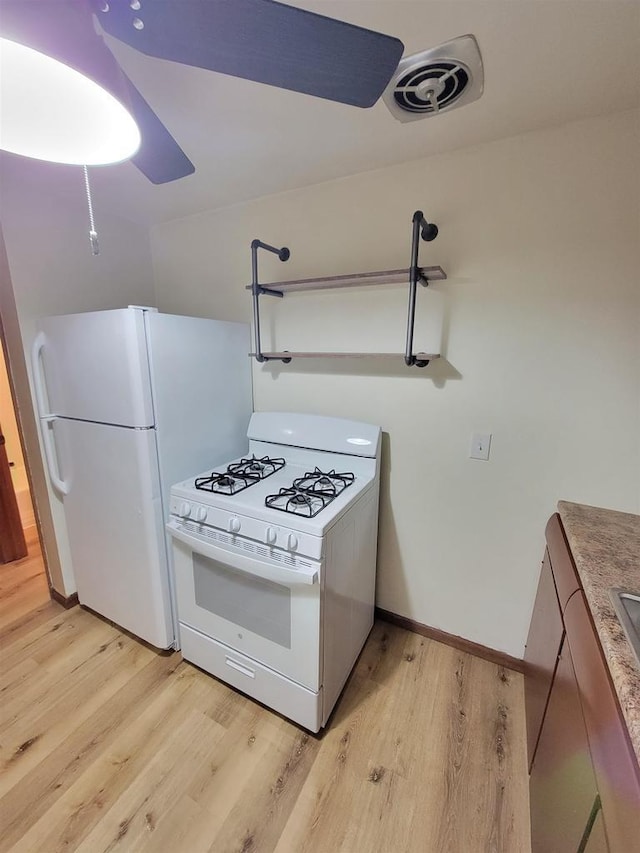 kitchen with white appliances, light wood-style flooring, baseboards, and visible vents