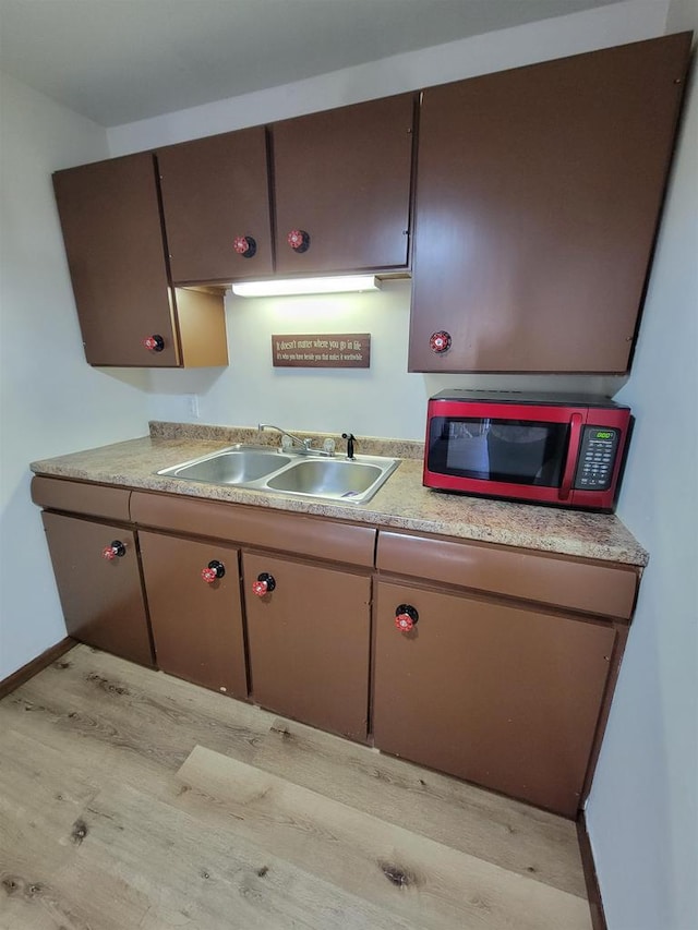 kitchen with light countertops, light wood-style floors, baseboards, and a sink