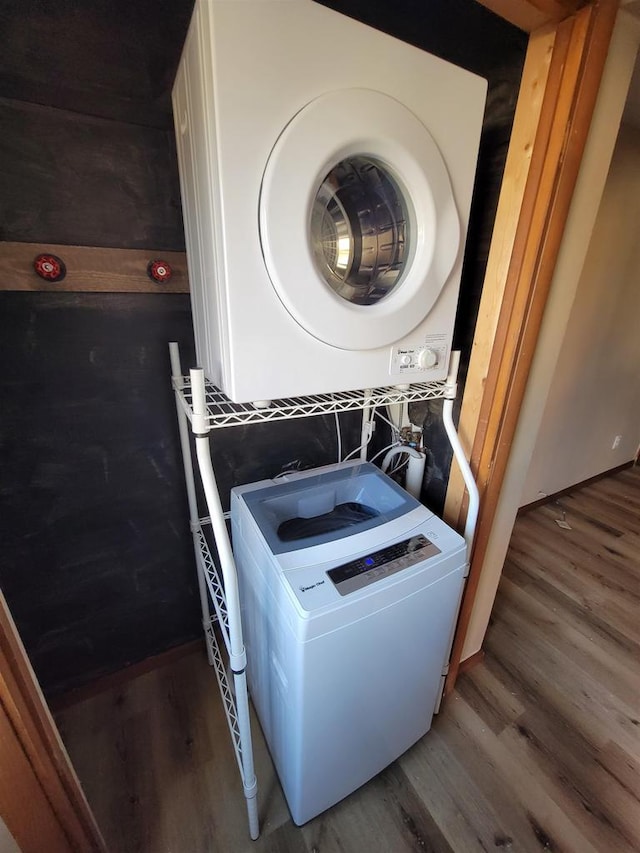 laundry area with laundry area, stacked washer and clothes dryer, and wood finished floors