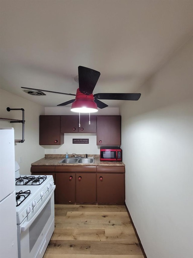 kitchen featuring white appliances, visible vents, light wood-style flooring, ceiling fan, and a sink