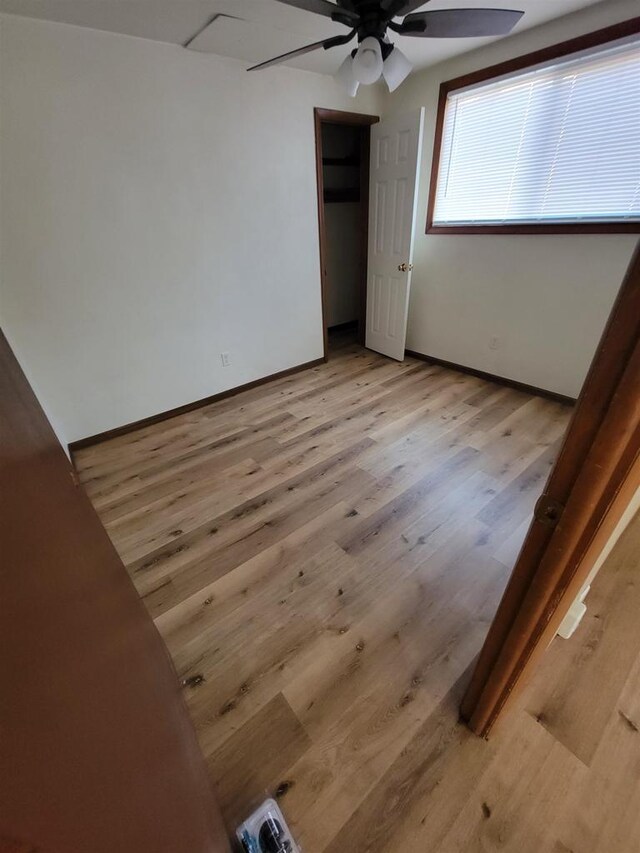 empty room featuring baseboards, light wood finished floors, and ceiling fan