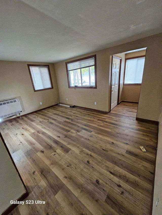 empty room with wood finished floors, baseboards, and a wall mounted air conditioner