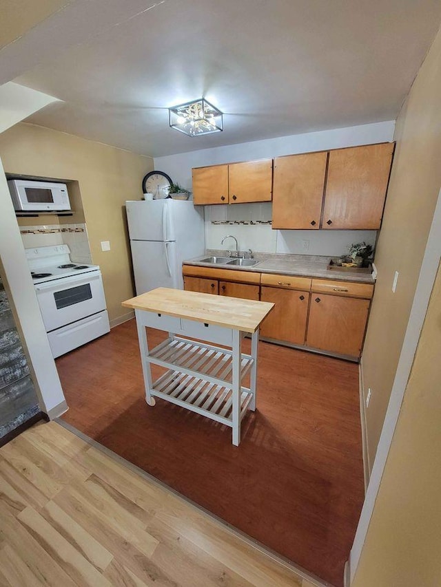 kitchen with light wood-style flooring, a sink, backsplash, white appliances, and light countertops