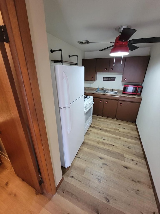 kitchen featuring baseboards, ceiling fan, light wood-style flooring, white appliances, and a sink