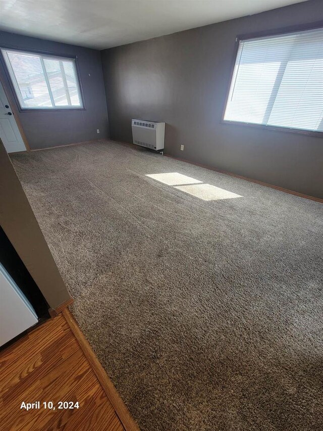 unfurnished room featuring heating unit and carpet