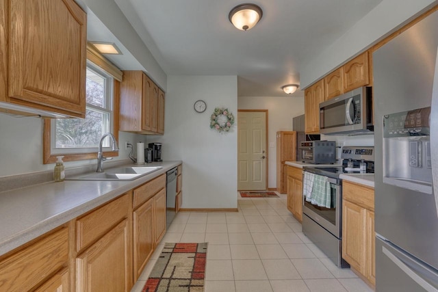 kitchen featuring a sink, stainless steel appliances, light tile patterned flooring, light countertops, and baseboards