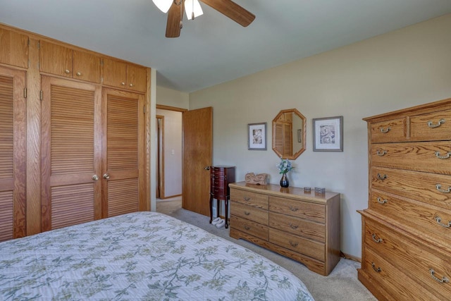 bedroom with a closet, light colored carpet, baseboards, and a ceiling fan