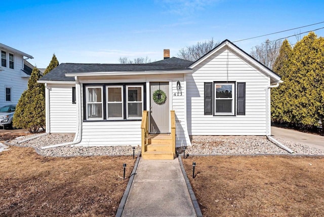 bungalow featuring entry steps, a chimney, and roof with shingles