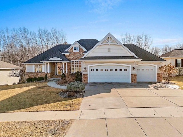 view of front of home with stone siding, driveway, a front yard, and a garage