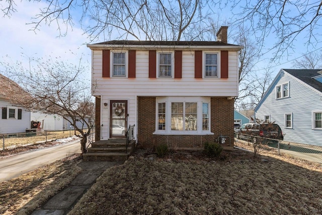 colonial-style house featuring fence, brick siding, and a chimney