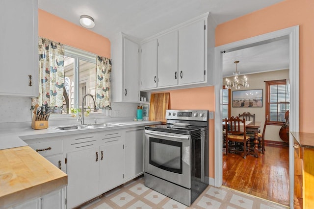 kitchen with light floors, stainless steel range with electric cooktop, light countertops, and a sink