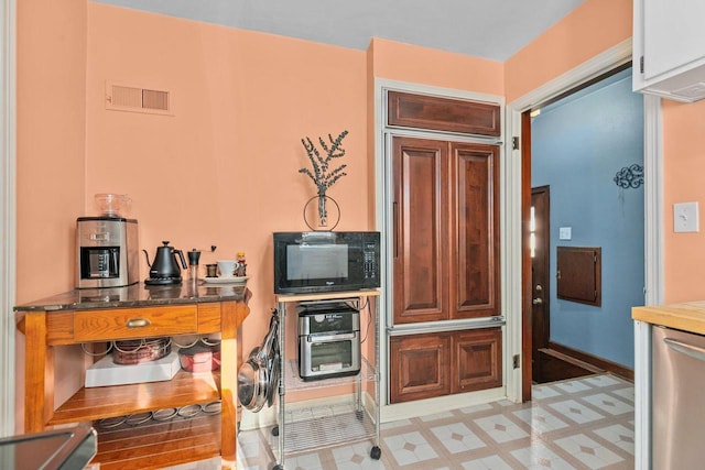 kitchen with visible vents, light floors, black microwave, and stainless steel dishwasher