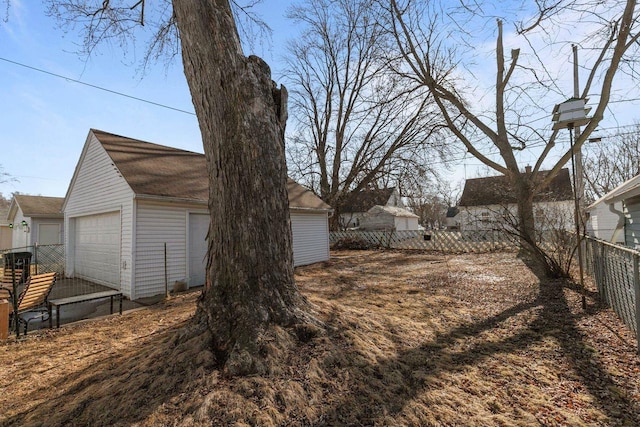 view of yard with a detached garage, an outbuilding, and fence