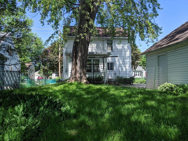 back of house featuring a lawn and fence