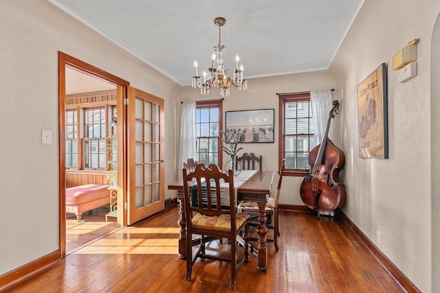 dining room with baseboards, wood-type flooring, an inviting chandelier, and crown molding