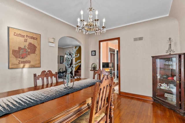 dining space with visible vents, baseboards, ornamental molding, wood finished floors, and arched walkways