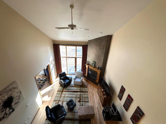 living room featuring a glass covered fireplace, wood finished floors, and a ceiling fan