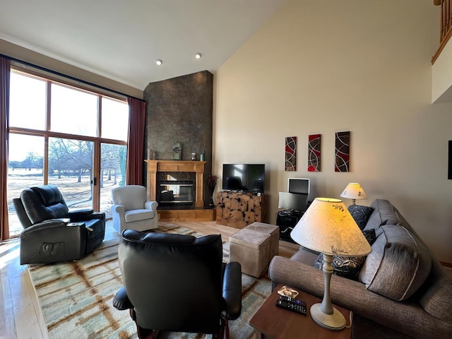 living room featuring a high ceiling, a glass covered fireplace, and light wood finished floors