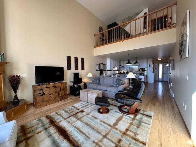 living room with light wood-type flooring, baseboards, and a towering ceiling