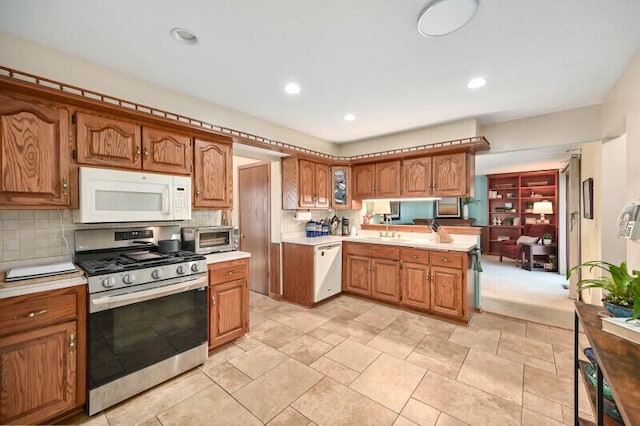 kitchen with white appliances, a peninsula, decorative backsplash, light countertops, and brown cabinets