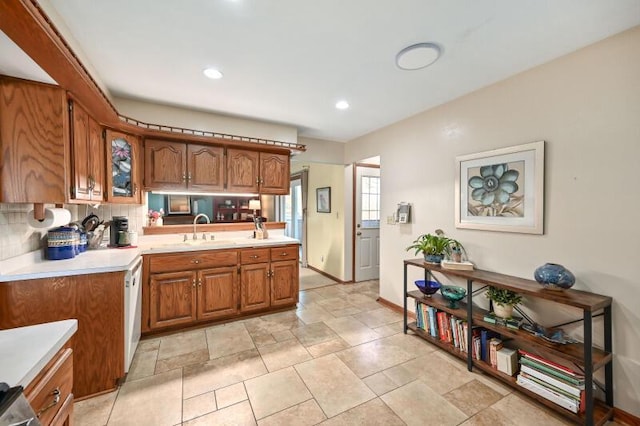 kitchen featuring a sink, decorative backsplash, brown cabinets, and light countertops