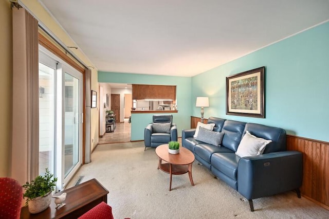 living area featuring wooden walls, carpet floors, and a wainscoted wall