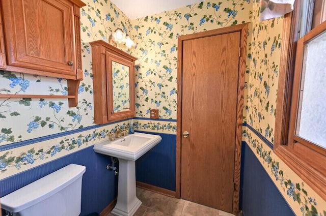 bathroom with a sink, toilet, tile patterned flooring, and wallpapered walls