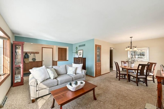 living area with visible vents, light carpet, a notable chandelier, and baseboards