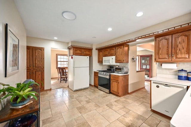 kitchen featuring backsplash, white appliances, light countertops, and brown cabinets