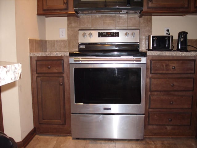 kitchen with light countertops, stainless steel range with electric stovetop, tasteful backsplash, and ventilation hood